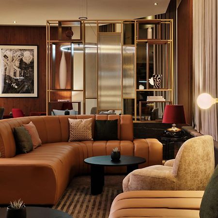Radisson Blu Hotel Krakow Exterior photo The photo shows a modern and stylish lounge area. It features a curved, multi-colored sectional sofa with a combination of beige, brown, and green upholstery. There are various decorative cushions on the sofa, adding a touch of comfort. In front of t