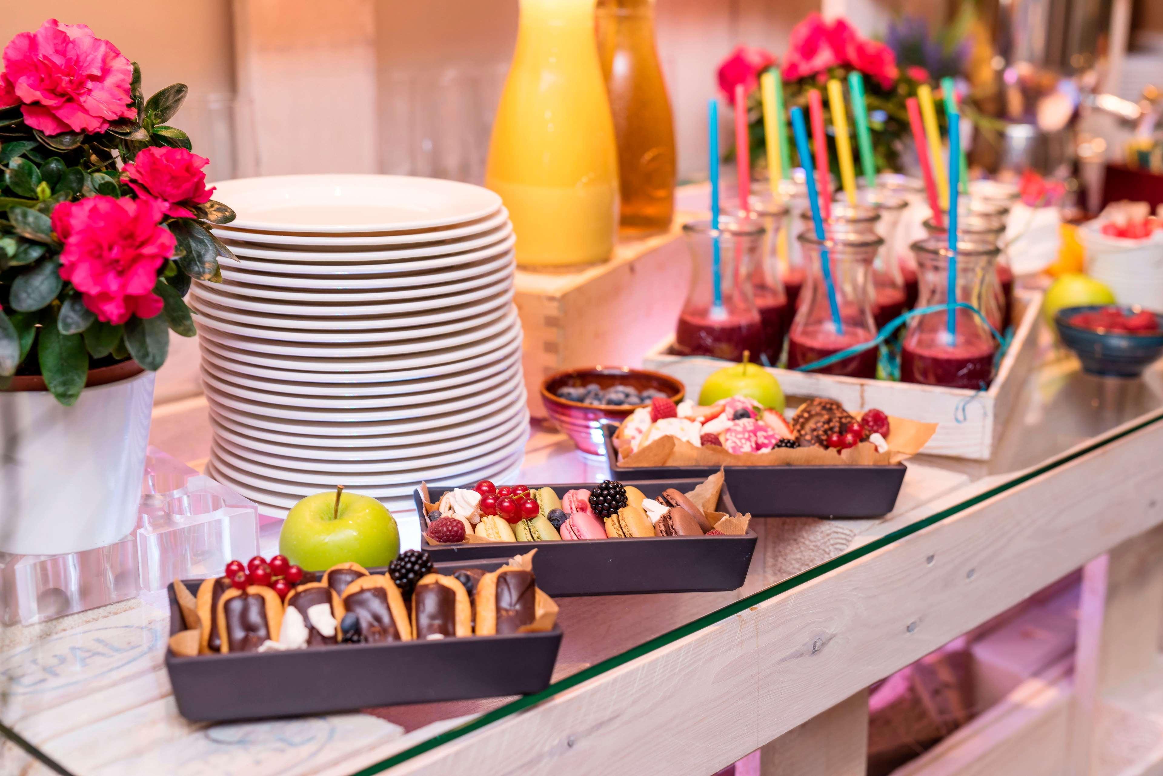 Radisson Blu Hotel Krakow Exterior photo The photo displays a charming buffet setup featuring various food items. In the foreground, there are three trays filled with desserts, including chocolate-covered treats, fruits, and possibly mini pastries. An apple sits among the desserts. Behind t