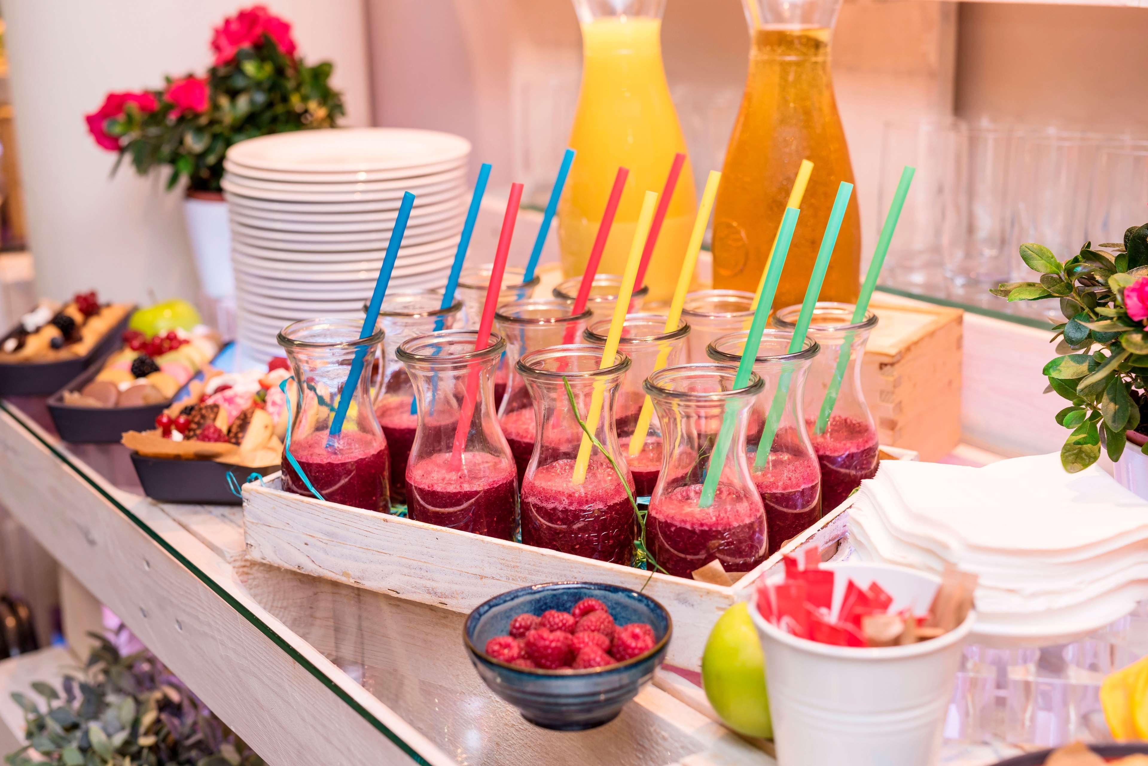 Radisson Blu Hotel Krakow Exterior photo The photo depicts a colorful beverage display. There are several small glass bottles filled with a deep red smoothie or juice, each equipped with a colorful straw. Next to these bottles, there is a bowl of fresh raspberries. In the background, there 