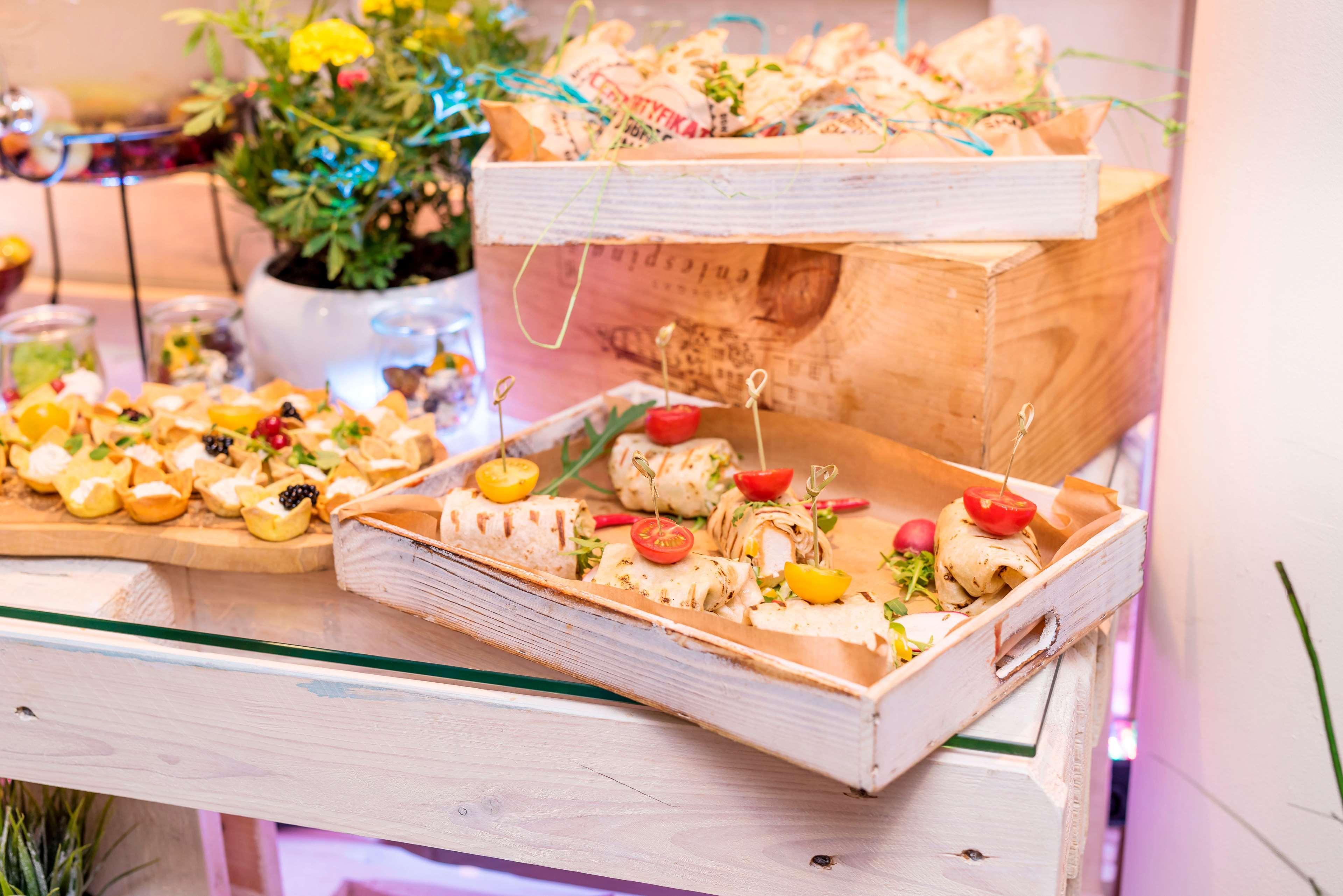 Radisson Blu Hotel Krakow Exterior photo The photo displays an elegant food presentation featuring two trays of bite-sized appetizers. 

In the foreground, a wooden tray holds assorted canapés topped with various garnishes, including pieces of vegetables and herbs. There are small skewers h