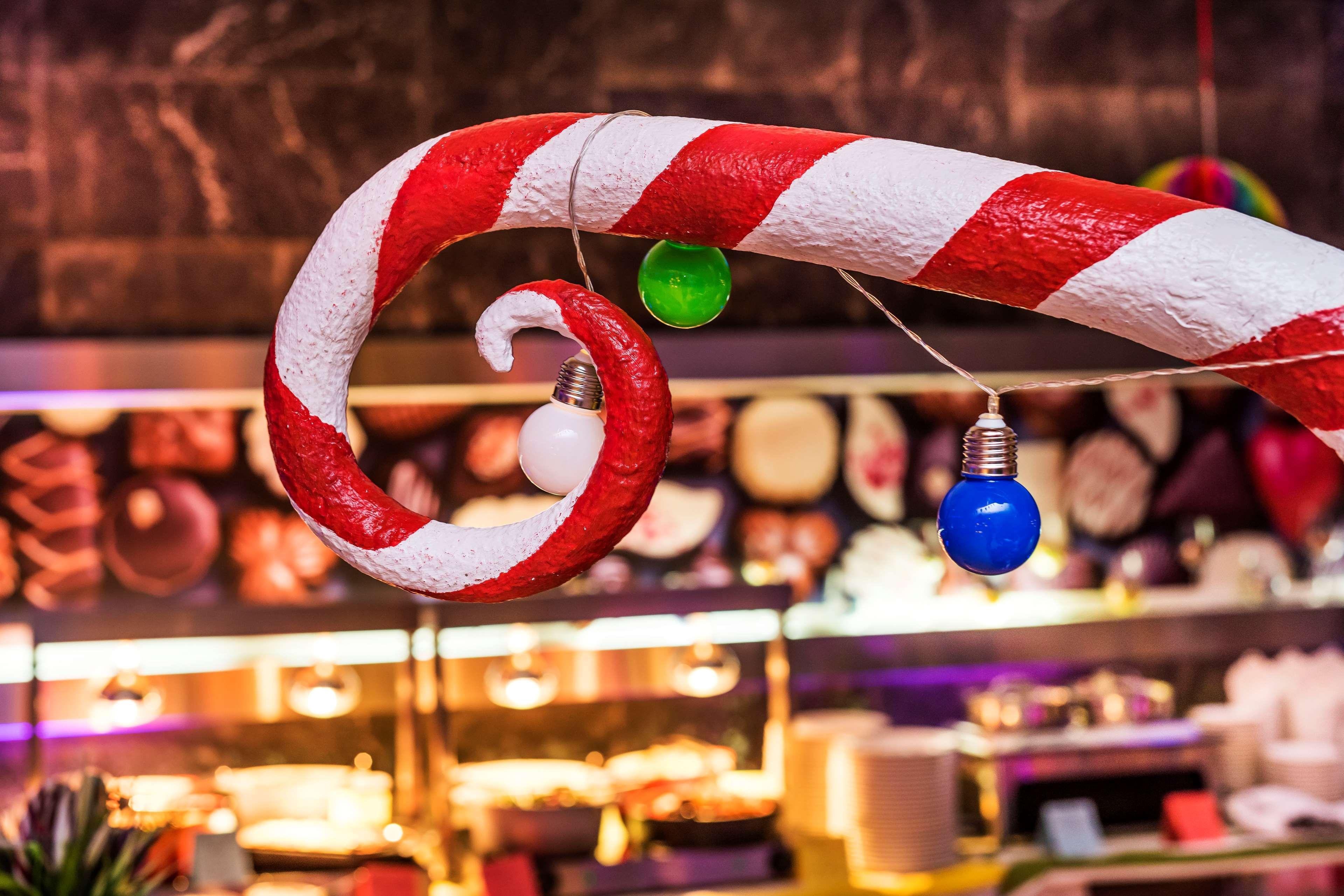 Radisson Blu Hotel Krakow Exterior photo The photo shows a colorful decoration resembling a candy cane, with red and white stripes. It features a spiral shape, and several light bulbs are hanging from it. The bulbs are in different colors, including green, blue, and white. In the background