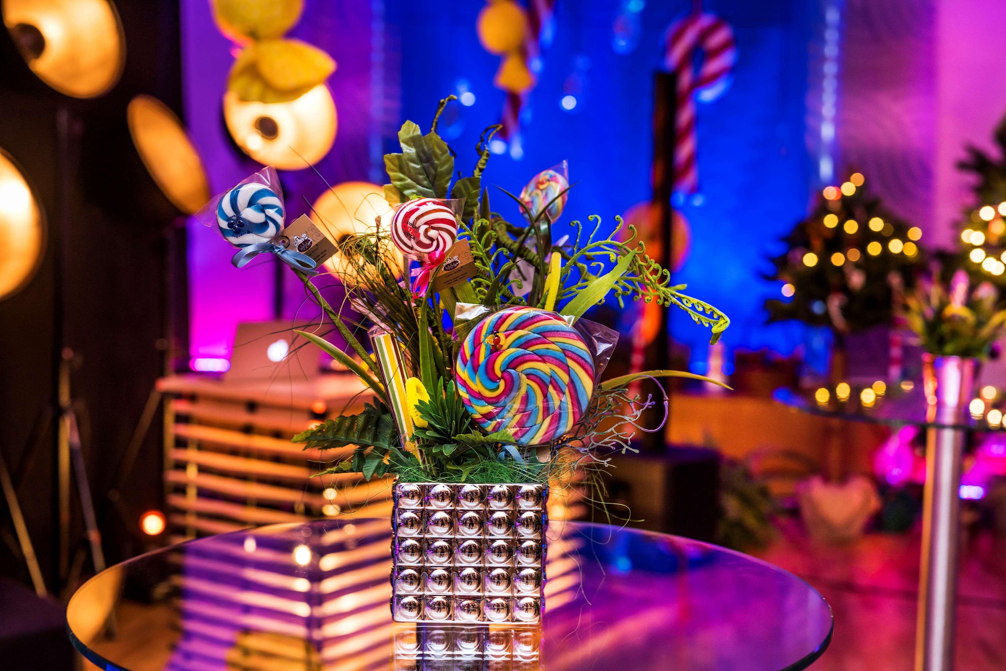 Radisson Blu Hotel Krakow Exterior photo The photo shows a decorative arrangement featuring colorful lollipops arranged in a shiny metallic vase. The bouquet includes various types of lollipops, particularly one large spiral lollipop with vibrant colors. Surrounding the lollipops are green 