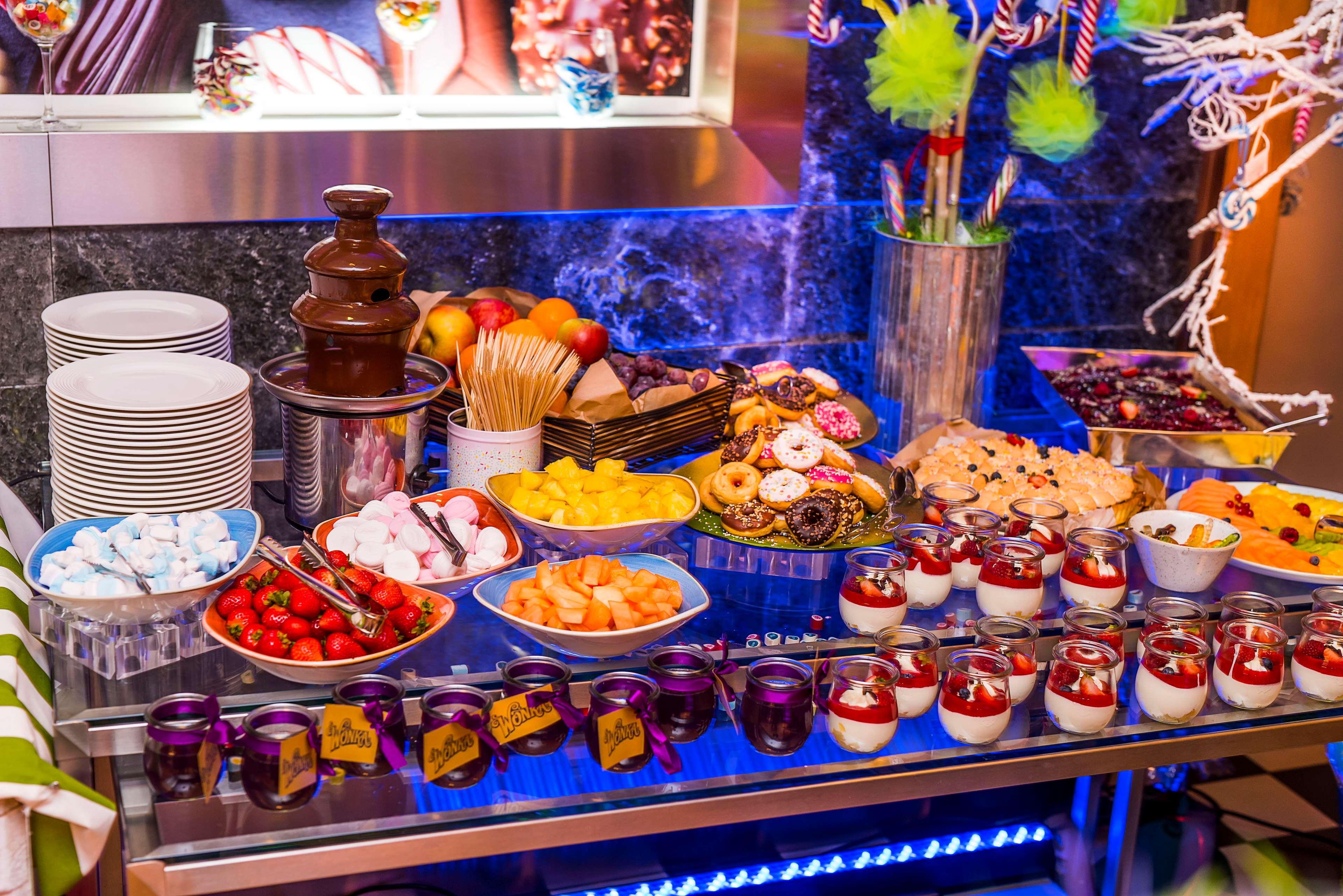 Radisson Blu Hotel Krakow Exterior photo The photo displays a vibrant dessert buffet with a variety of sweet treats and snacks. There is a chocolate fountain in the center, surrounded by plates of fruits such as strawberries and pineapple. Additionally, there are cookies, donuts, and small 
