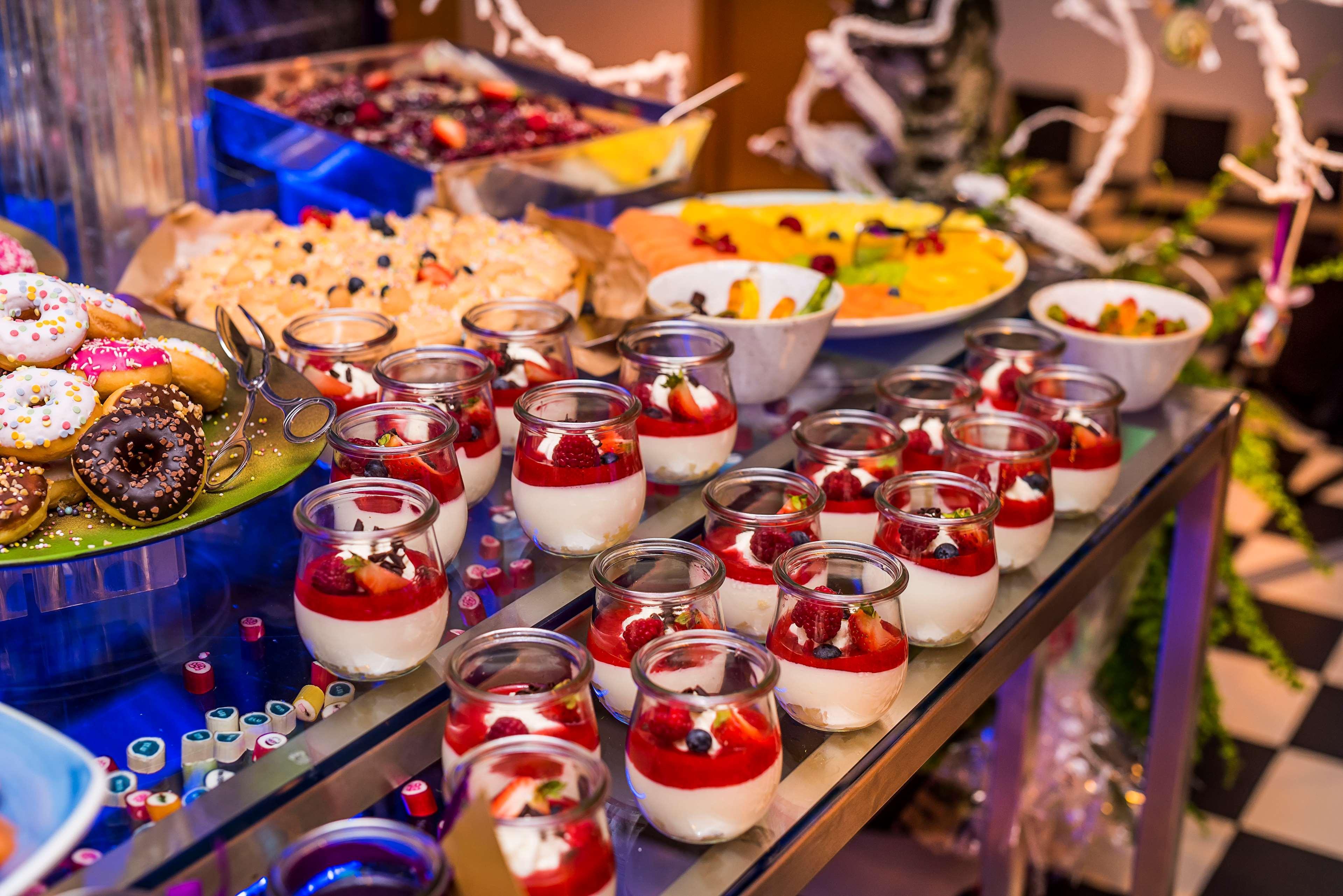 Radisson Blu Hotel Krakow Exterior photo The image displays an array of desserts beautifully arranged on a table. In the foreground, there are small glass containers filled with a layered dessert, featuring a white creamy base topped with red fruit and garnished with berries. In the backgro