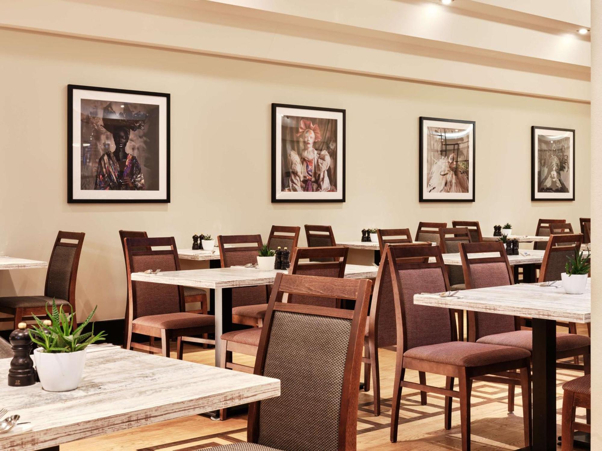 Radisson Blu Hotel Krakow Exterior photo The image shows a restaurant interior featuring a series of tables and chairs arranged neatly. The tables have a simple, modern design with light-colored surfaces. Brown chairs are set around the tables, some with dark cushions. The walls are decorat