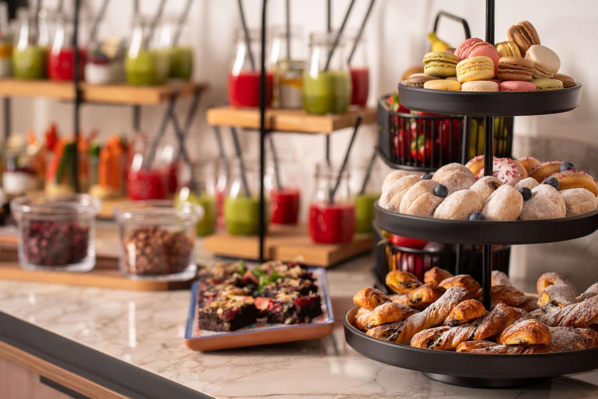 Radisson Blu Hotel Krakow Exterior photo The photo depicts a beautifully arranged buffet spread featuring a variety of food items. In the foreground, there is a tiered stand with an assortment of pastries, including small cakes, cookies, and baked treats. Some of the items appear to be deco